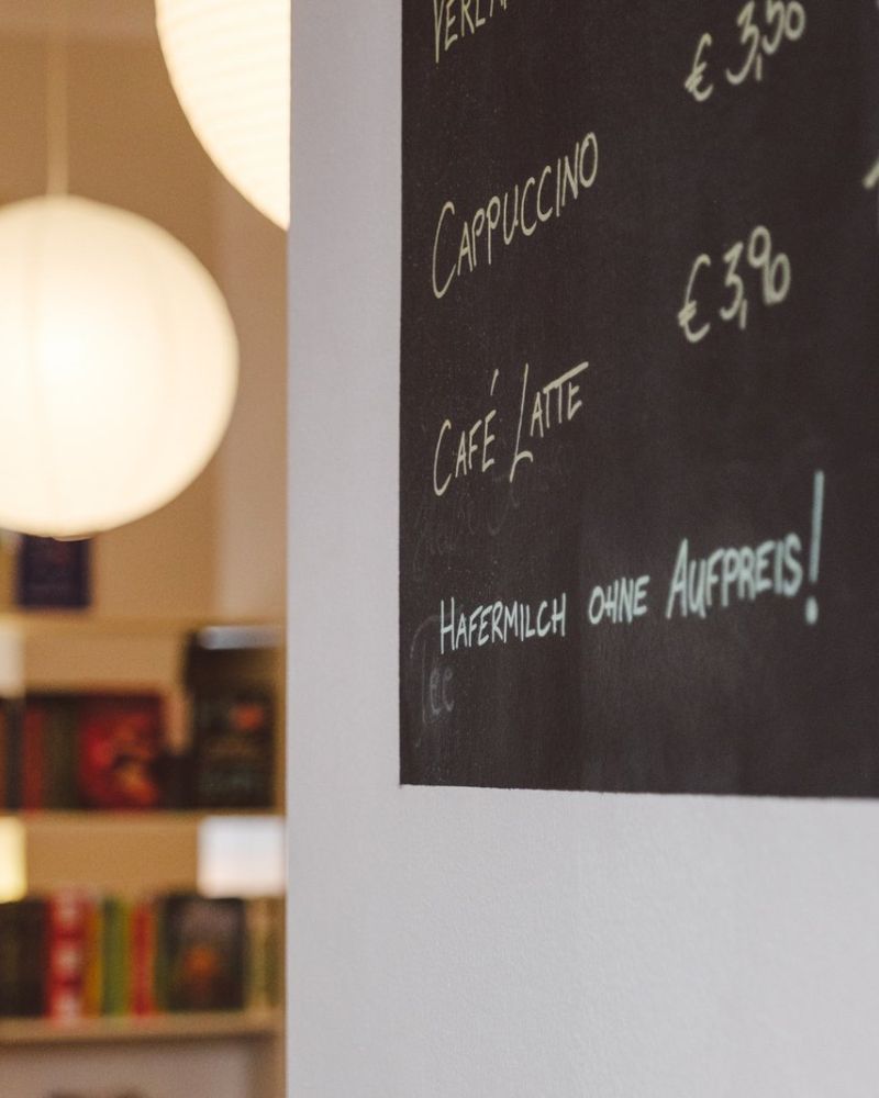Runde Leuchten vor einer schwarzen Tafel mit dem Kaffeeangebot des BuchQuartier-Cafés
